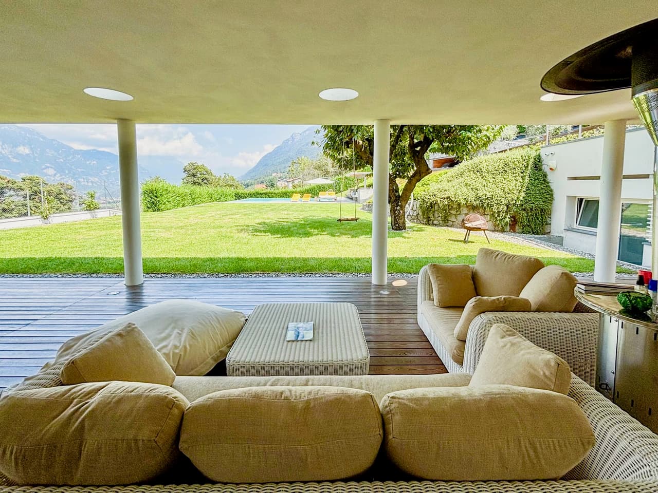 Villa Panoramica — portico con divano in lino, colonne tornite e vista sulle Prealpi